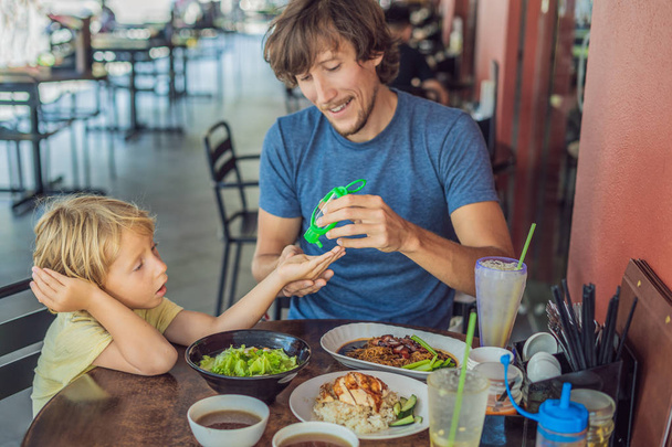 Father and son using wash hand sanitize gel before eating in a cafe. - Photo, image
