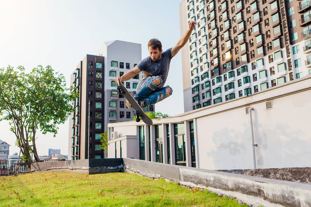 Young handsome man with beard on a skateboard jumping high and making trick - Photo, Image