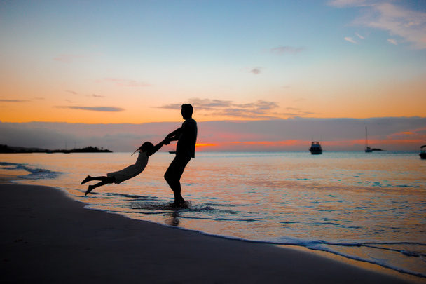 Bambina e felice silhouette padre al tramonto in spiaggia
 - Foto, immagini