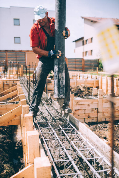 trabalhador industrial usando bomba de concreto para a construção de fundação casa. Detalhes do construtor no canteiro de obras
 - Foto, Imagem