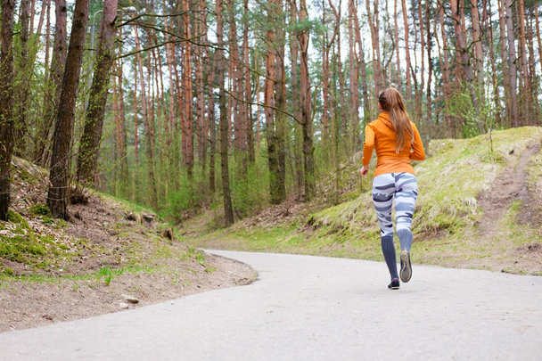 Mädchen in orangefarbenem Kapuzenpulli läuft durch Wald - Foto, Bild