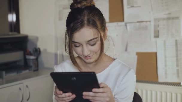 Adorable girl works with tablet and smiles at camera. 4K - Πλάνα, βίντεο