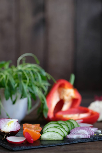 Fresh vegetables sliced for a salad on a cutting board, on an old wooden table - Φωτογραφία, εικόνα