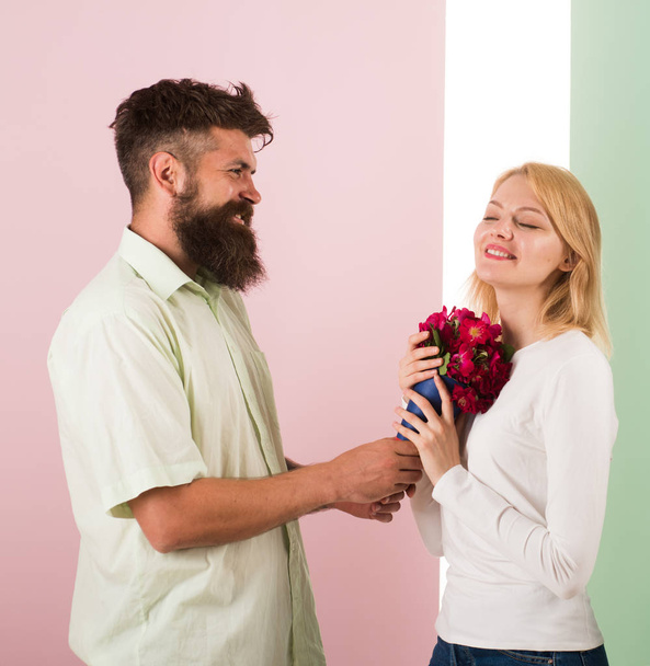Man with beard congratulates woman birthday anniversary holiday. Hipster bearded give bouquet flowers to girlfriend. Couple in love celebrating holiday. Couple date bouquet flowers gift. Gift concept - Foto, afbeelding