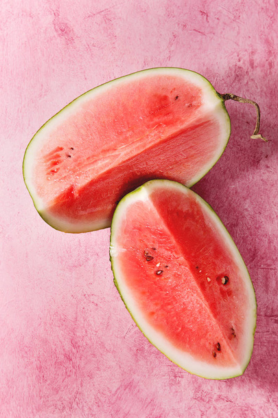 Ripe sliced watermelon over pink texture background. Flat lay, space. - Foto, afbeelding