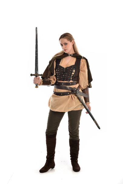 ritratto a figura intera di ragazza bionda che indossa un costume da guerriero medievale marrone. posa in piedi, isolato su sfondo bianco studio
. - Foto, immagini