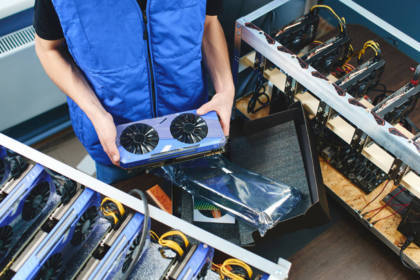 male hands holding video card for setting up farm of bitcoin mining - Foto, Imagen