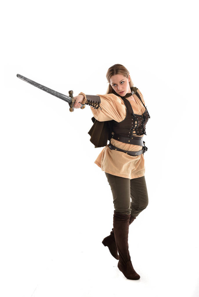 portrait complet de fille blonde vêtue d'un costume de guerrier médiéval brun. pose debout, isolé sur fond de studio blanc
. - Photo, image