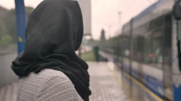 Young muslim woman in hijab is watching how train is coming under raining, religion concept, transport concept, weather concept - Záběry, video
