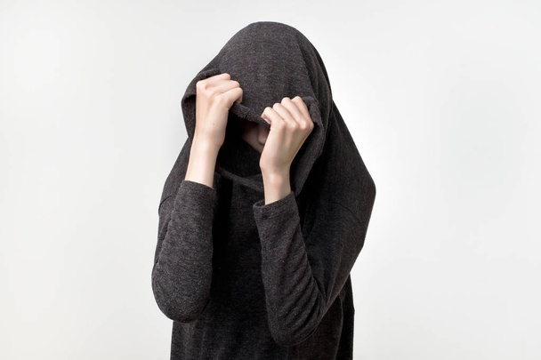 Vrouw verbergen gezicht onder de kleren. Ze is oulling sweatr op haar hoofd. Depressief emotie. Wil ba alleen. Bescherming van de persoonlijke ruimte - Foto, afbeelding