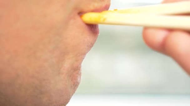 Close-up. mannelijke lippen in profiel. de man eet chopsticks, spaghetti met rode saus. 4k, slow-motion. - Video