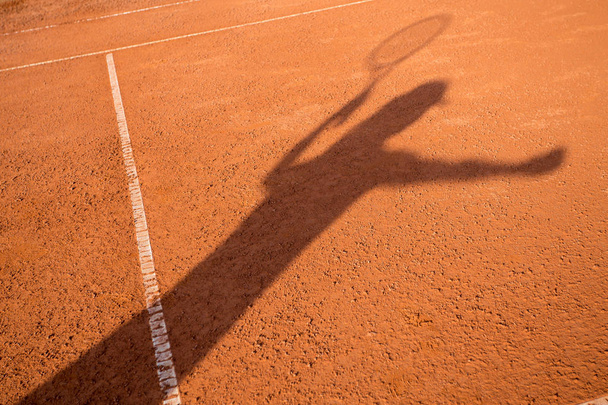 Shadow of a female tennis player serving outside - Foto, imagen