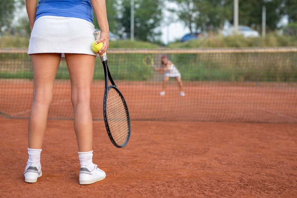 Γυναικεία πόδια σε ένα γήπεδο τένις με ρακέτα εκτός - Φωτογραφία, εικόνα
