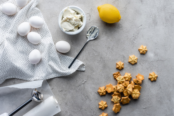 flat lay with arranged lemon, sour cream, raw chicken eggs and cookies for pie on grey surface - Foto, Bild