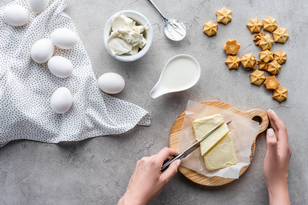 Oříznout záběr másla řezání žena na prkénku na domácí koláč na šedou desku - Fotografie, Obrázek