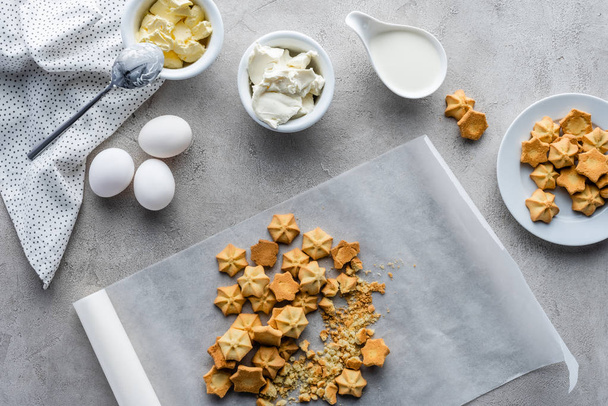 flat lay with cookies, raw chicken eggs, butter and sour cream for making pie arranged on grey tabletop - Fotografie, Obrázek