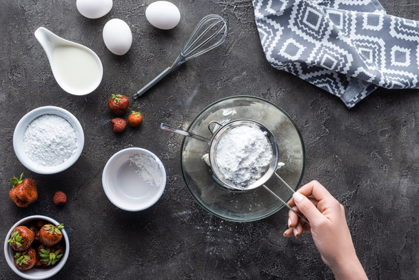 partial view of woman adding flour while making cream for homemade pie on dark grey tabletop - Foto, Imagem
