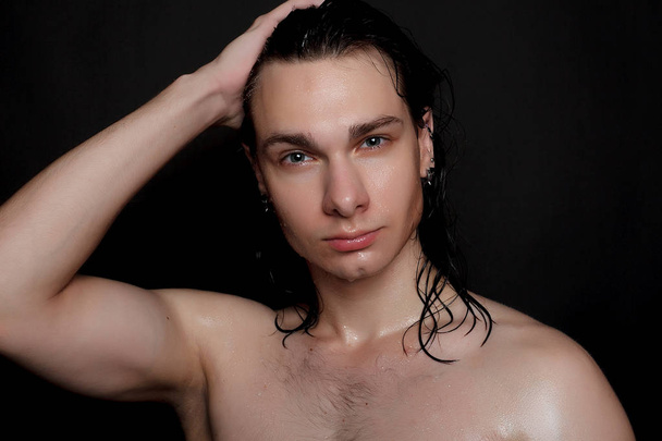people, skincare and beauty concept - Wet young man with long black hair on a black background. Portrait male with shaved chest . Men's skin care. Ripped muscular handsome man on black background - Фото, зображення