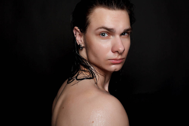 people, skincare and beauty concept - Wet young man with long black hair on a black background. Portrait male with shaved chest . Men's skin care. Ripped muscular handsome man on black background - Фото, изображение