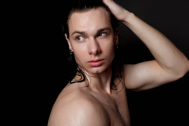 people, skincare and beauty concept - Wet young man with long black hair on a black background. Portrait male with shaved chest . Men's skin care. Ripped muscular handsome man on black background - Fotografie, Obrázek