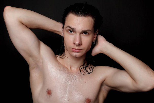 people, skincare and beauty concept - Wet young man with long black hair on a black background. Portrait male with shaved chest . Men's skin care. Ripped muscular handsome man on black background - Photo, Image