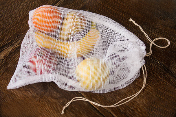 Sıfır atık, meyve (elma, portakal, armut ve bir muz) ya da sebze, bir ahşap yüzeye taşımak için plastik ücretsiz geri dönüşümlü tekstil üretim çanta. Çanta eski perdeleri dışında bir dikiş makinesi ile yapılır. - Fotoğraf, Görsel