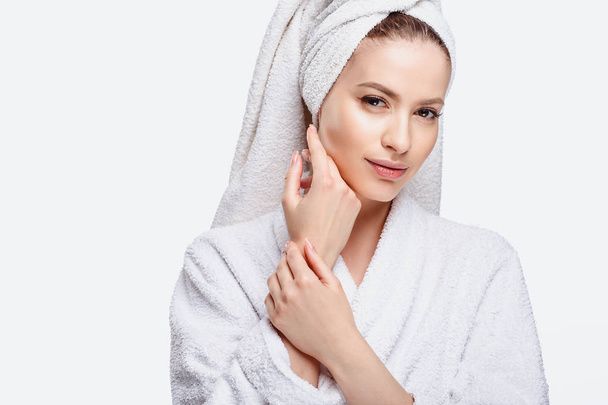 Young woman in a bathrobe and towel on her head, spa and care portrait, clean natural face, portrait on a white background isolated - Photo, image