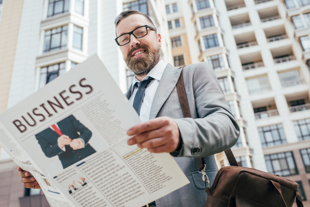 handsome bearded businessman holding business newspaper in city - 写真・画像