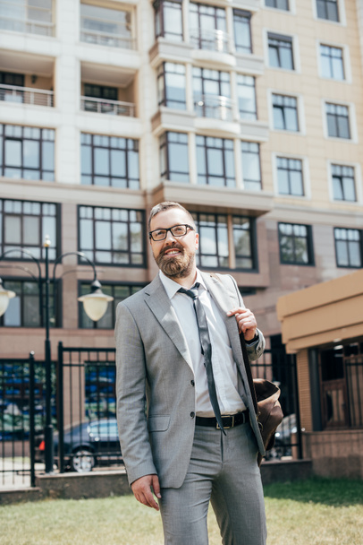 handsome bearded businessman in suit with leather bag in city - Photo, Image