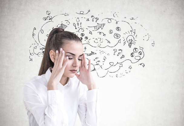 Stressed young businesswoman with long hair in a ponytail wearing a white shirt. She is having a headache and standing with closed eyes. An arrow sketch on a concrete wall. - 写真・画像