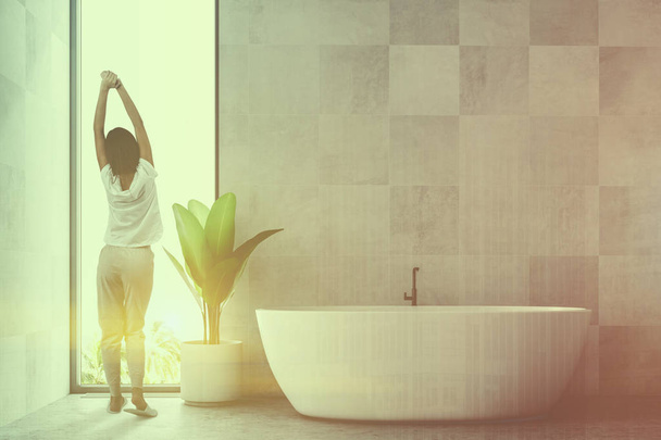 White wooden tile bathroom interior with a concrete floor and a white bathtub standing near a potted plant. A loft window and a woman. 3d rendering mock up toned image double exposure - Photo, image