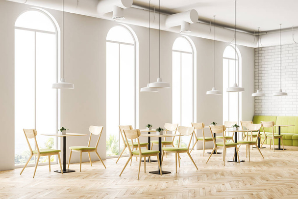 Industrial style cafe interior with white brick walls, a wooden floor, arched windows and wooden tables with chairs and green sofas. 3d rendering mock up - Foto, Imagen