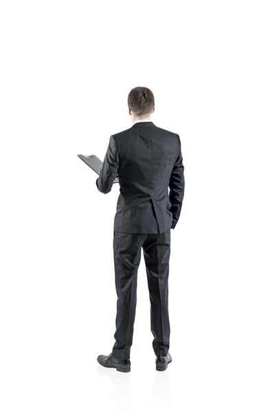Rear view of a young businessman in a gray suit holding a folder. He is looking forward. Concept of business lifestyle. An isolated portrait. - Fotoğraf, Görsel