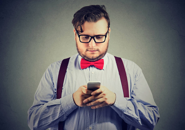 Eccentric beard business man with red bow tie in glasses using a smartphone - Photo, image