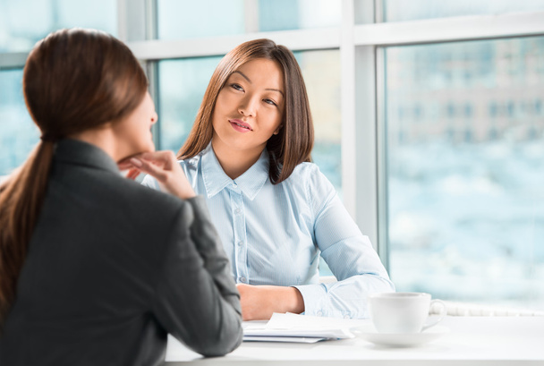 Two business women talking and signing contract at office - Фото, изображение