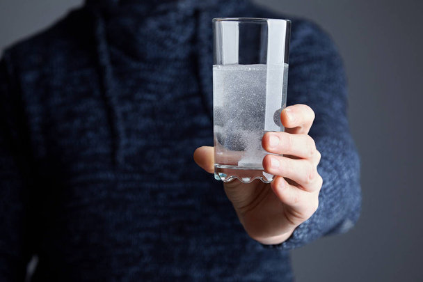 Homme tenant un verre avec une pilule dissoute dans l'eau. Pilule blanche soluble et un verre d'eau dans ses mains. Effervescent comprimé aspirine dans un verre d'eau
 - Photo, image