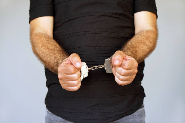 Крупним планом. Заарештований чоловік в наручниках. Ув'язнений або заарештований терорист, крупним планом руки в наручниках, вибірковий фокус
. - Фото, зображення