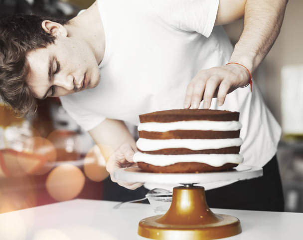 Young attractive man baking cake - Фото, изображение
