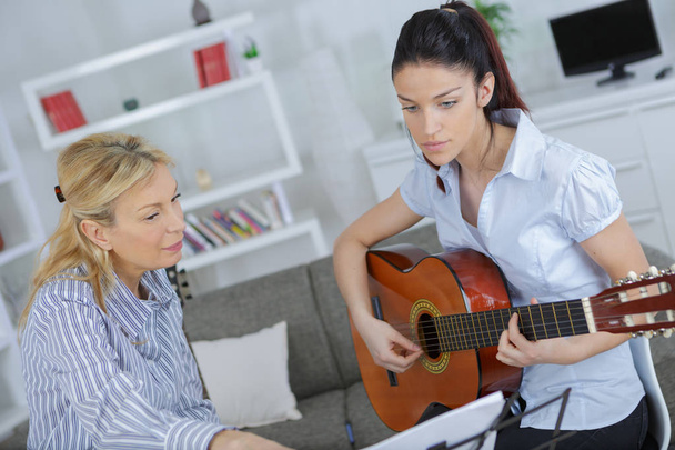 female teaching her young female to play guitar - 写真・画像