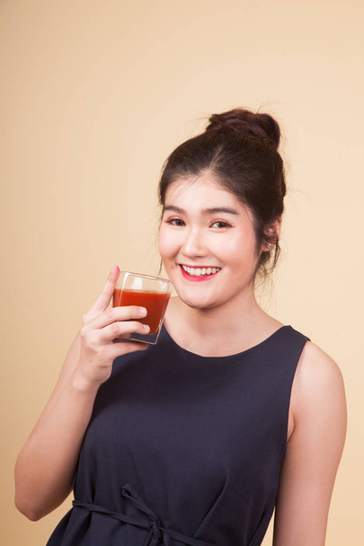 Young Asian woman thumbs up with tomato juice  on beige background - Foto, imagen