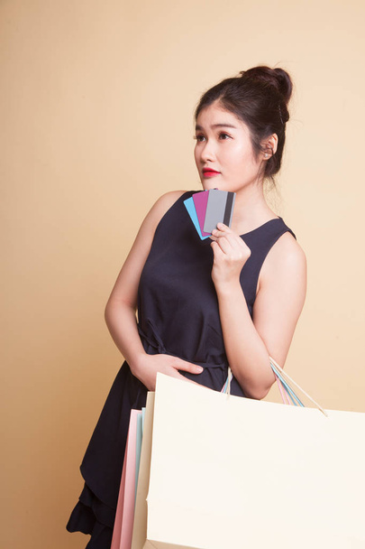 Young Asian woman with shopping bag and blank card  on beige background - Φωτογραφία, εικόνα