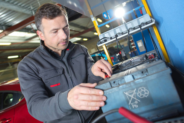 auto mechanic checks voltage level in car battery - Photo, Image