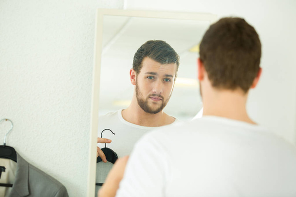 young man trying shirt on in front of mirror - Photo, image