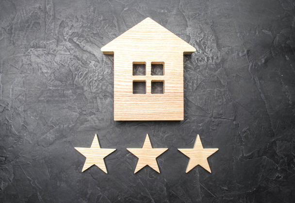Wooden house and three stars on a gray background. Rating of houses and private property. Buying and selling, renting apartments. The level of the restaurant and hotels. Rating five stars. - Фото, зображення