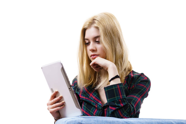 Young teenage woman using tablet while sitting on sofa and relaxing surfing on internet - Foto, Imagem