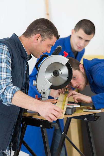 carpinteiro sênior com dois aprendizes aprendendo
 - Foto, Imagem