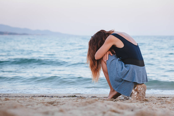 Woman alone and depressed sitting at the beach - Photo, Image