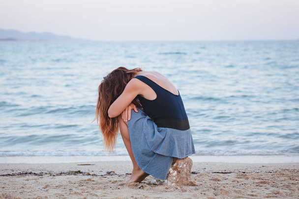 Nainen yksin ja masentunut istuu rannalla
 - Valokuva, kuva