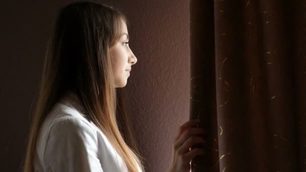 Gyönyörű fiatal nő nézett ki az ablakon - Felvétel, videó