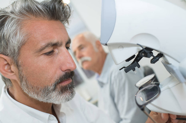 portrait of mid adult male scientist using microscope in laboratory - Foto, afbeelding